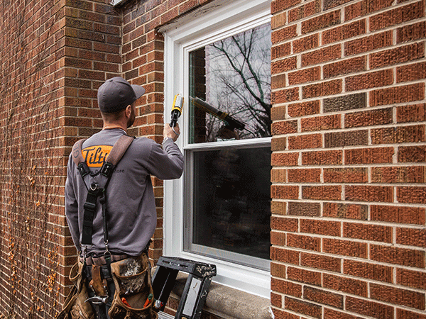 Tiltin installer working on a replacement window at a brick home