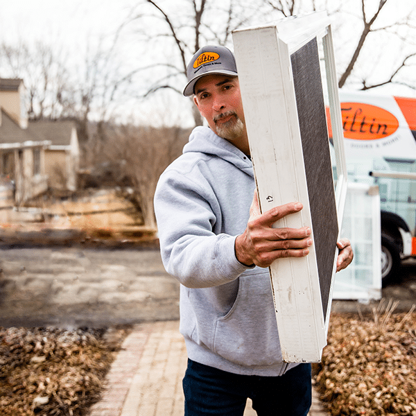 Tiltin crew member carrying a replacement window from the company van