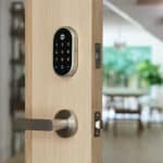 Keyless smart lock installed on a wooden front door inside a modern home.